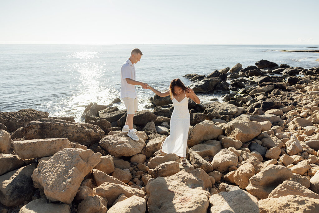 Newly married couple walking along a quiet beach in Alicante during their honeymoon at sunset.